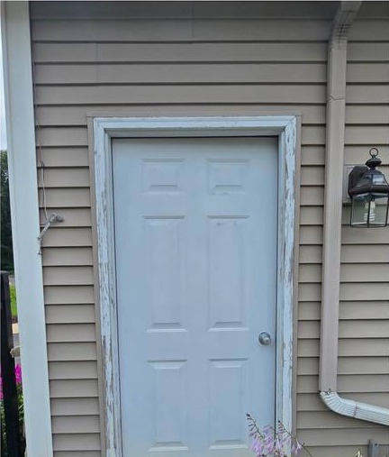 Worn wood entry door with a rotted frame at a home in Lowell, Michigan before replacement